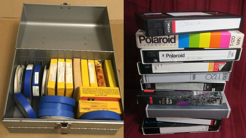 A tin box of film reels next to a leaning stack of VHS tapes
